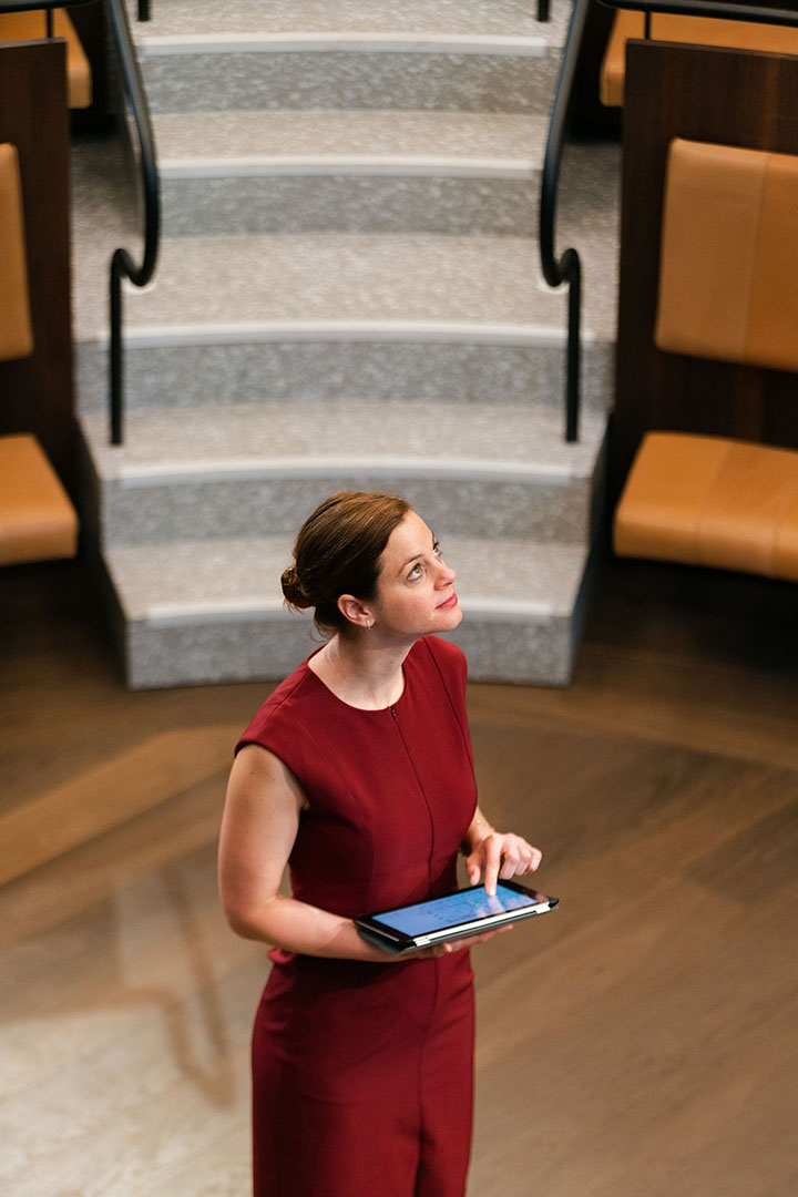Image of woman carrying a tablet device in a lecture theatre